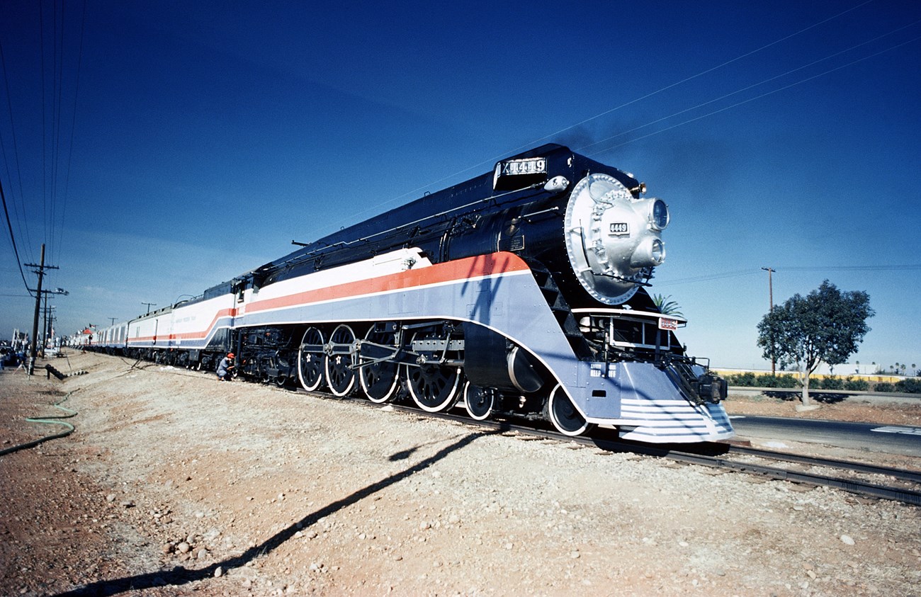 Train speeding across tracks surrounded by dirt.