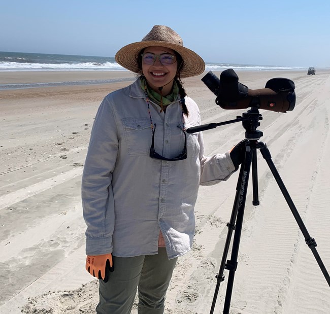 Abigail Gonzalez with the Southeast Coast Network Woman standing on the beach with a camera