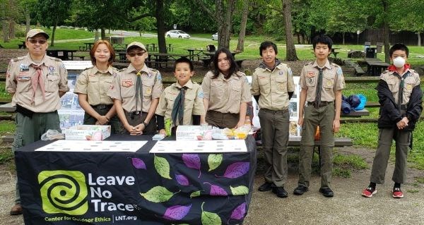 Members of Troop 55 stand behind a table with a Leave No Trace Tablecloth. They are all in their Boy Scouts of America uniforms.