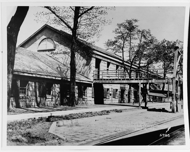 street view of a long building. A long walkway juts out from the second story towards the end of the building.