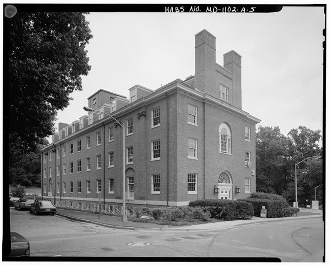 Corner view of three-story Georgian Revival brick building.