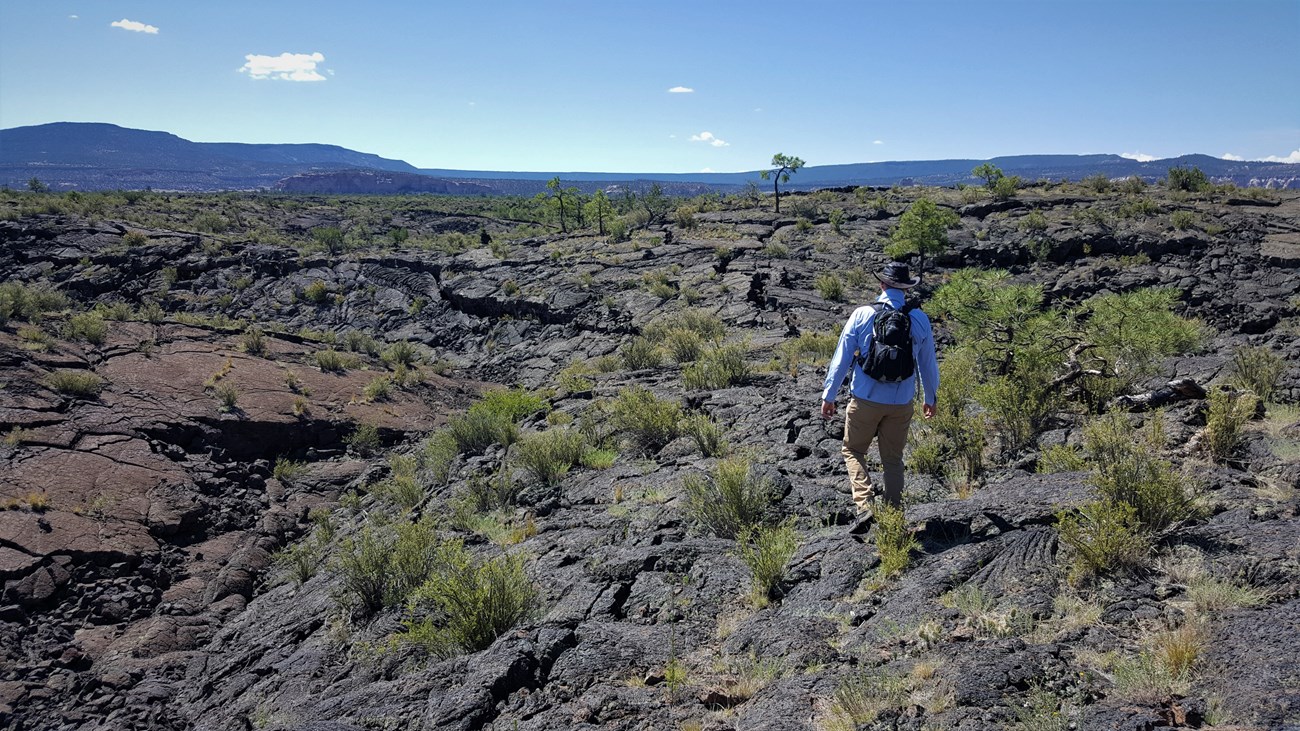 Hiker walking over a lava flow in the desert