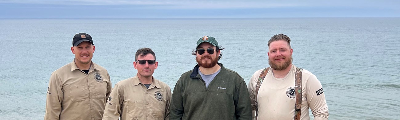 2025 Veterans Fire Corps crewmembers at Cape Cod National Seashore Four men stand in front of large body of water.