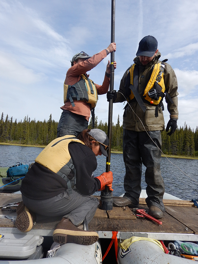 3 people on a raft hold onto a pole-like piece of equipment