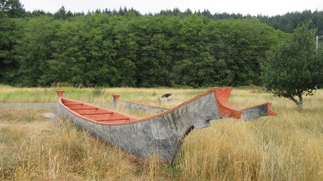 Wooden canoe in grassy field.