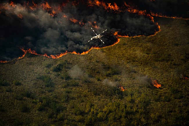 Aerial view looking down on helicopter in flight above burning south Florida landscape. Aerial view looking down on helicopter in flight above burning south Florida landscape.