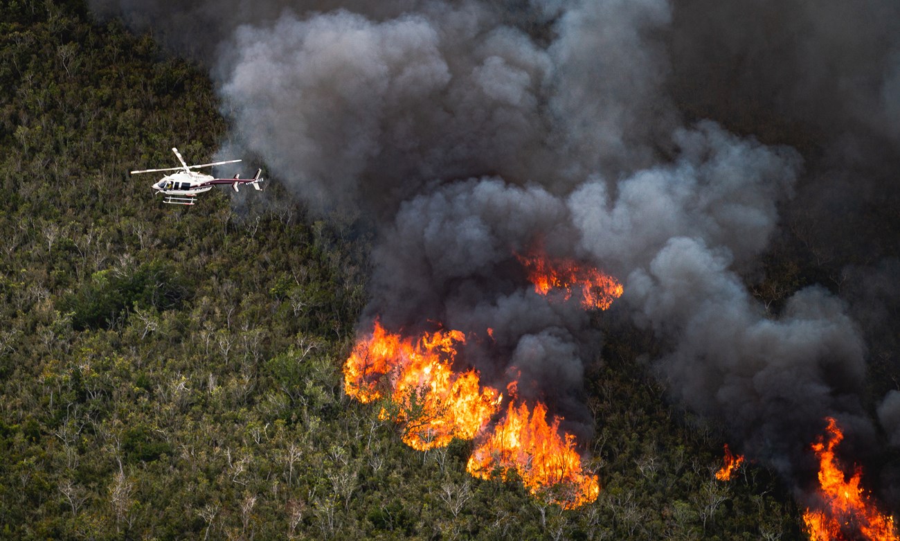 Interceptor Fire in south Florida A helicopter flies over a burning forest.