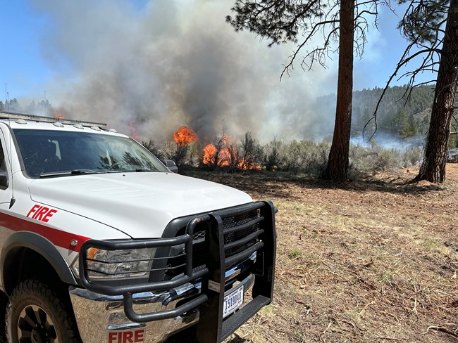 Southeast corner of North Casino prescribed fire. A wildland fire engine parked near area where fire is burning.