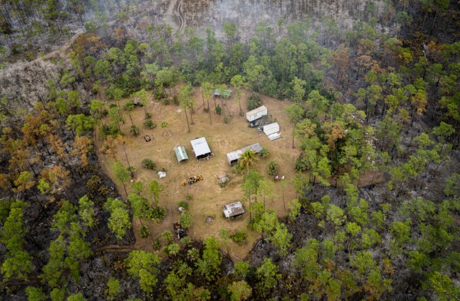 Aerial view of several buildings in a clearing within a forested area