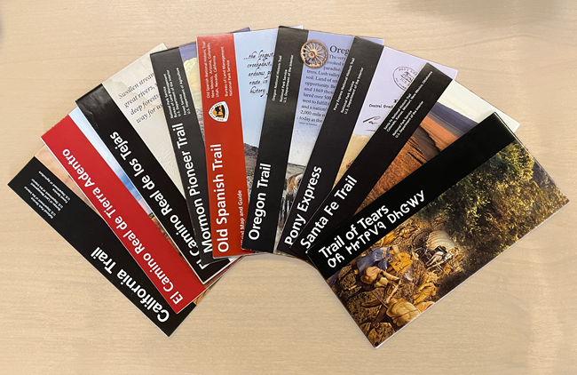 Nine national historic trail folder brochures laid out on a table in a fan shape.