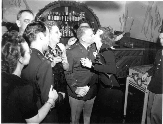 a man and woman kiss while onlookers cheer