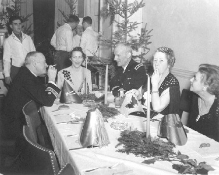 a group of military men and their wives sit around a dinner table