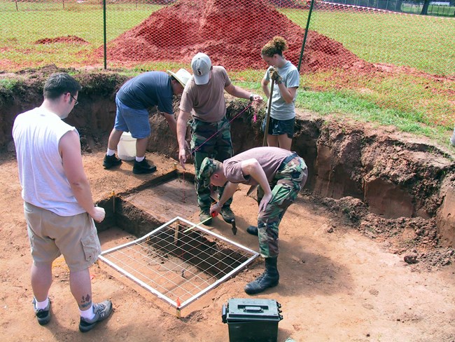 Archeology students examine an excavation pit at a Caddo site.