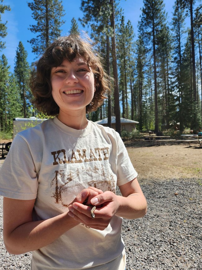 Natalie DiNenno Smiling young woman with brown hair holding a small snake.