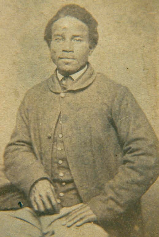 NathanSprague Portrait of an African American man sitting down wearing a coat over a collared shirt and waistcoat.
