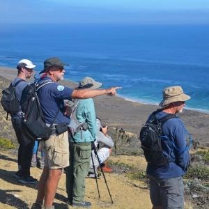 Channel Islands Naturalist Corps A volunteer giving an interpretative talk to visitors points to a large body of water.