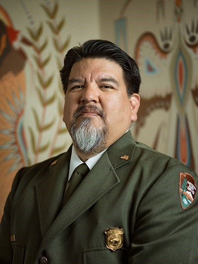 Portrait of Chuck Sams in NPS uniform. He has black hair and a beard.