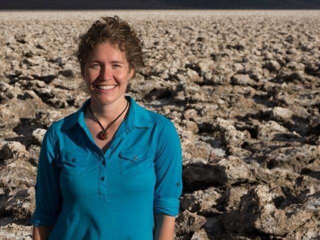 Nicole Hupp Woman facing camera smiling, standing in arid desert landscape.