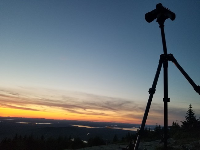 Use a tripod to create a sturdy set up for photographing the night skies with long exposures A camera on a tripod set up in front of a sunset