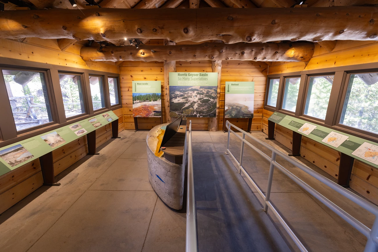 Norris Museum in Yellowstone An interior space with exhibits showing photos and text. Wooden floors, walls, and ceiling.