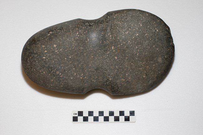 Gray stone axe head with a concave groove around the center.