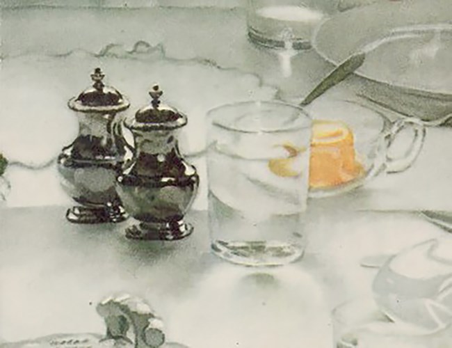 A glass of water sits on a set table. Beside it are silver salt and pepper shakers.