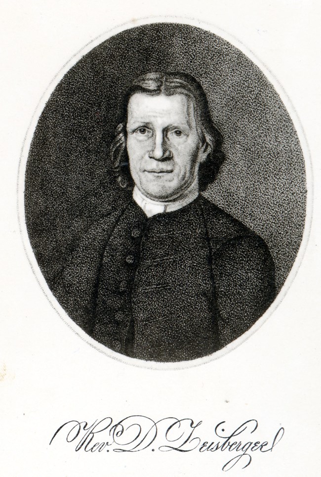 Etched, oval portrait of a man with a square jaw; white collar; dark, buttoned coat; and wavy hair.