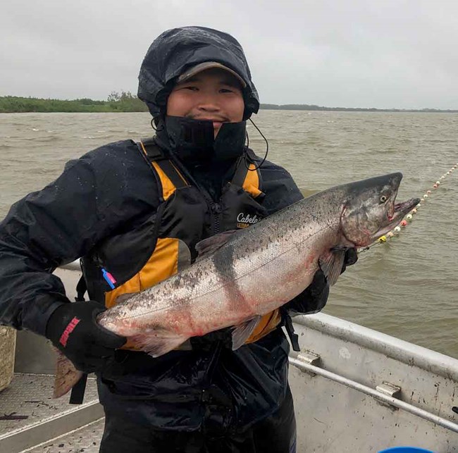 A young man holds up a king salmon.