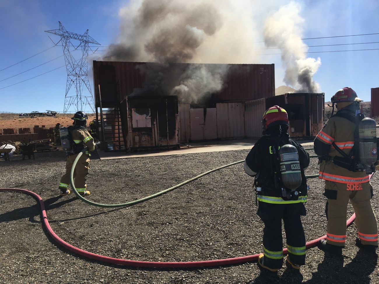 Structural firefighters spray water on a burning structure.