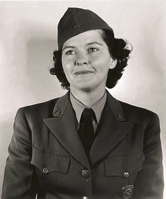 Olive Johnson_c1947 A woman with dark curled hair smiles at the camera. She is wearing an NPS uniformed jacked and her badge can be seen pinned to her chest.
