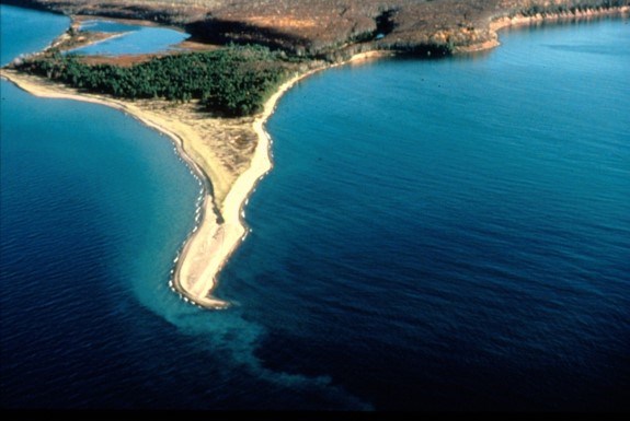 Aerial view of an island with sand beach surrounded by blue water.