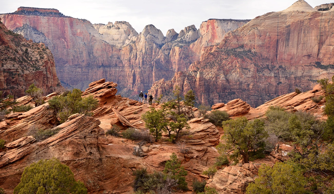 Three hikers looking out over the rocky landscape from the Overlook Trail in Zion. Three hikers looking out over the rocky landscape from the Overlook Trail in Zion.