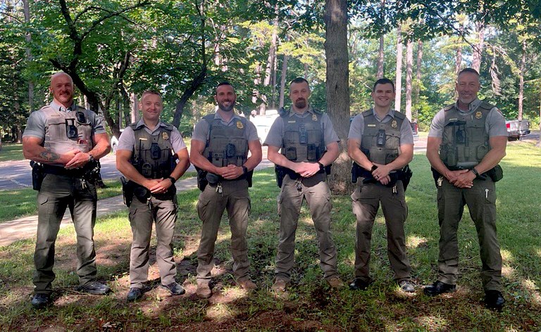 A group of people standing in a line in tan uniforms and straw flat-brimmed hats.