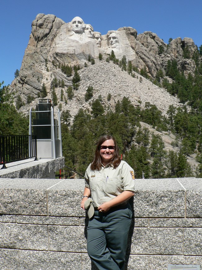 A young woman in a uniform standing in front of Mount Rushmore