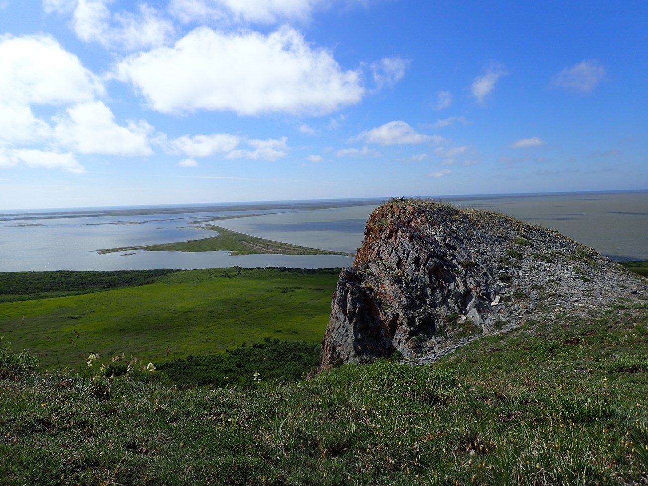 Krusenstern Lagoon Krusenstern Lagoon, a large lagoon spans the background as viewed from a rocky perch in the flowering tundra in the foreground.