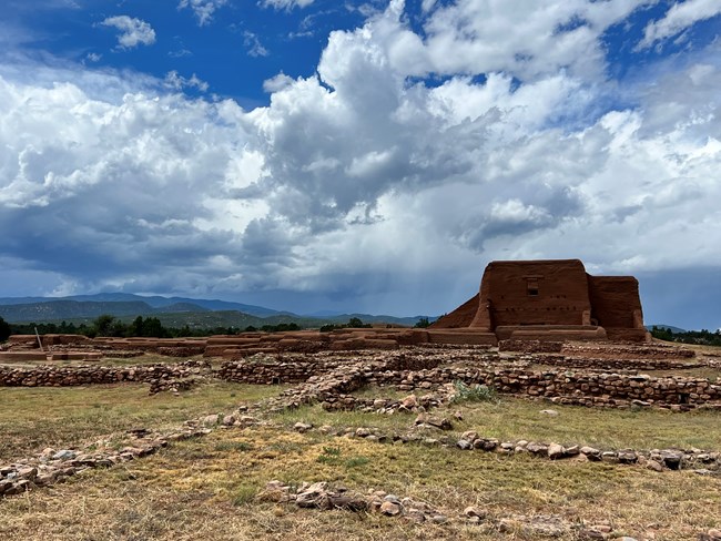Pecos Church An old adobe church sits on a grassy plain surrounded by rubble.