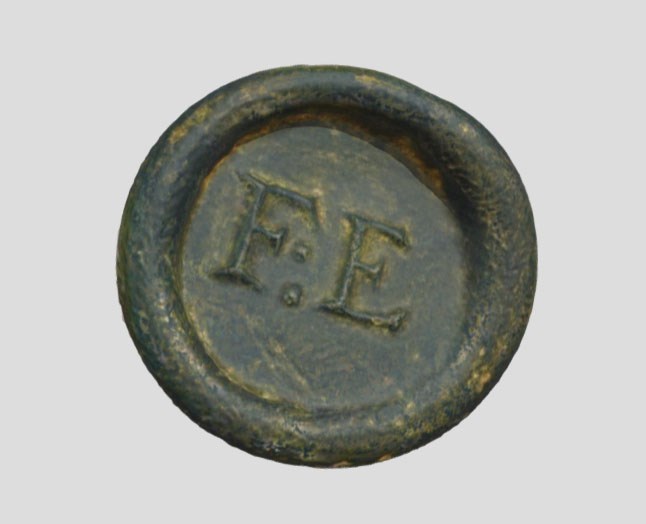 Wine bottle seal embossed with the letters FE Circular shape embossed with FE