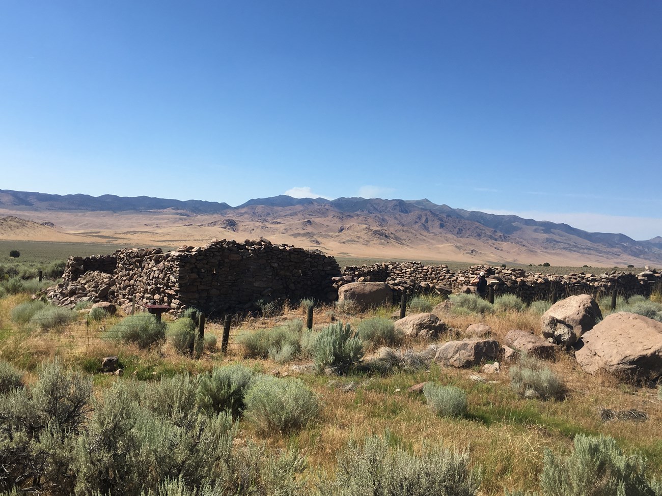 A ruin of a stone wall with distant desert mountains.