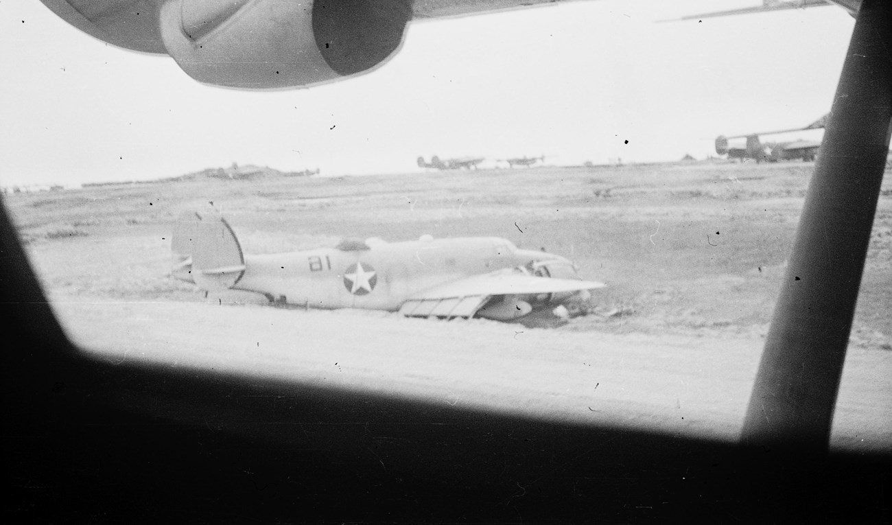 View from under a plane's wing to another plane on the runway