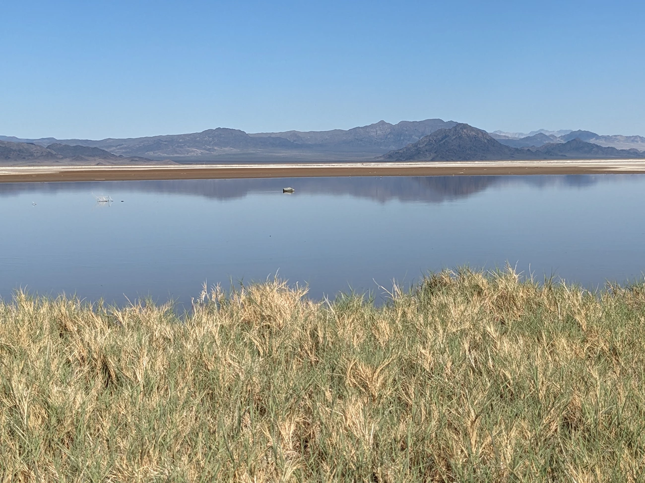 Often dry lakebed filled with water An expanse of shallow water is a temporary lake in the Mojave Desert, reflecting mountains on the opposite lakeshore..