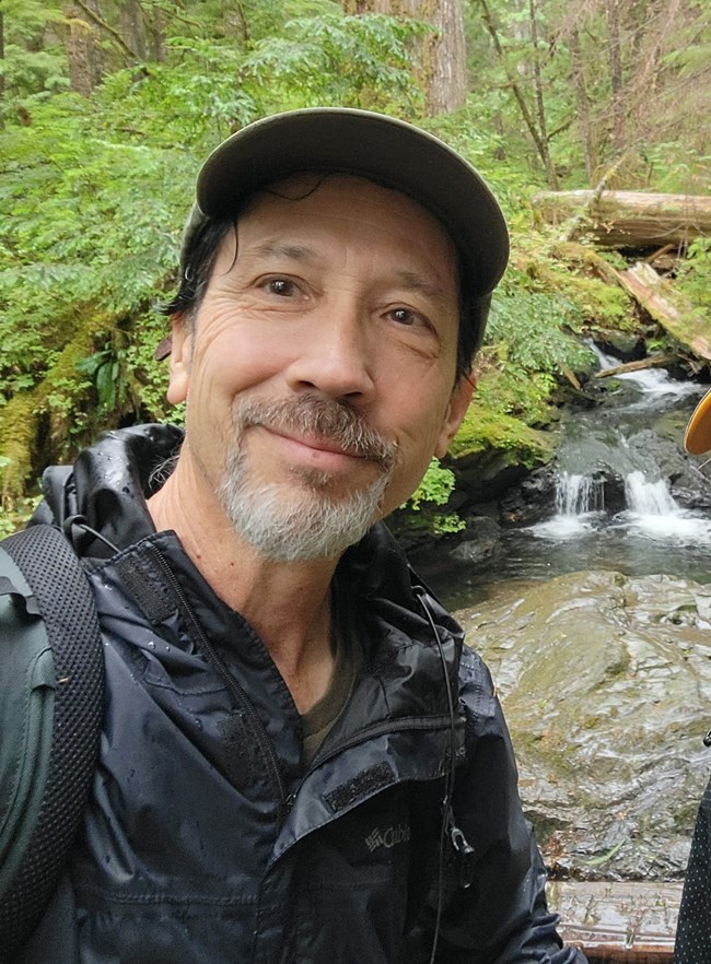 Smiling face of man with creek in background.