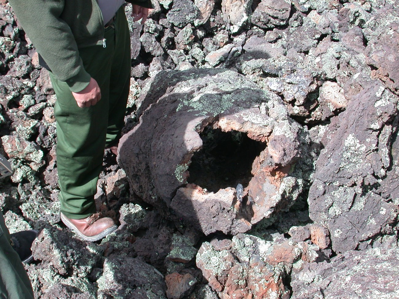 photo of a ringer standing by a round hole in a rocky surface