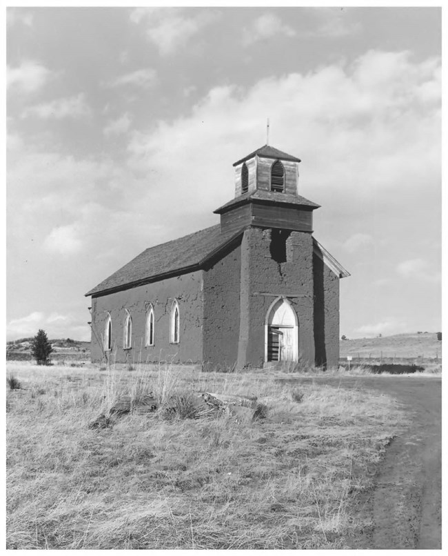 lt= A historic image of a church with one steeple, in a grassy field.
