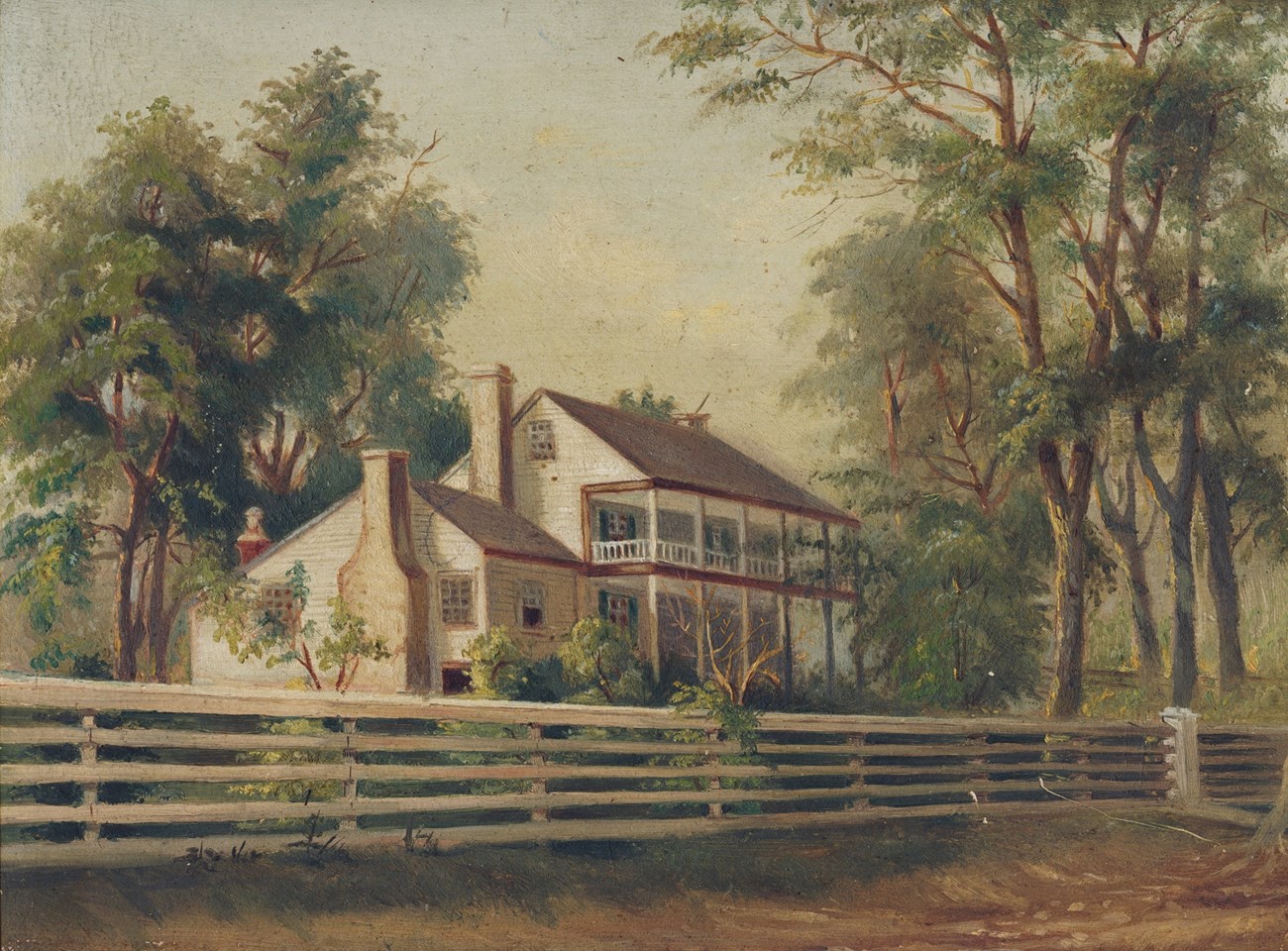 White two-story frame house surrounded by trees, grass, and a white fence.