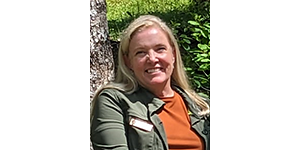 Pam Ziesler Headshot of Ziesler outside by a tree, smiling. She wears an orange shirt with a green outer layer with an NPS name badge affixed to it.