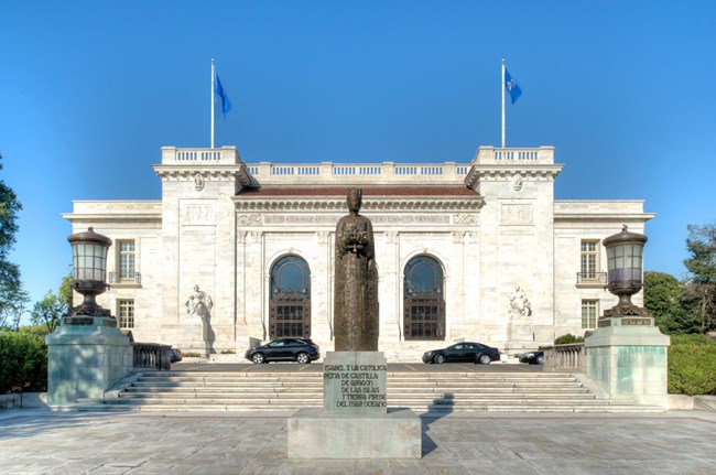 Pan-American Union Building Monumental white marble building with triple-arched entrance behind bronze statue of a woman