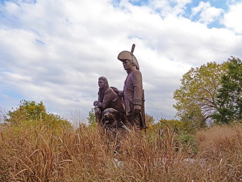 Park A statue of Lewis, Clark and Lewis’ dog Seaman. Tall, brown grass is in the foreground, and trees and a partially clouded sky are in the background.