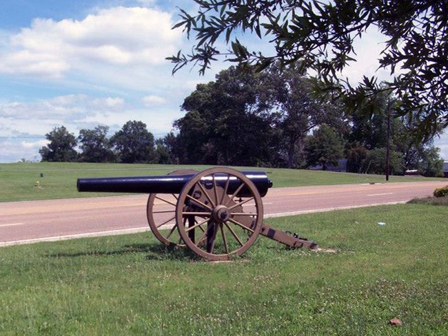 Parker’s Cross Roads battlefield Cannon sits in grassy field, divided by highway