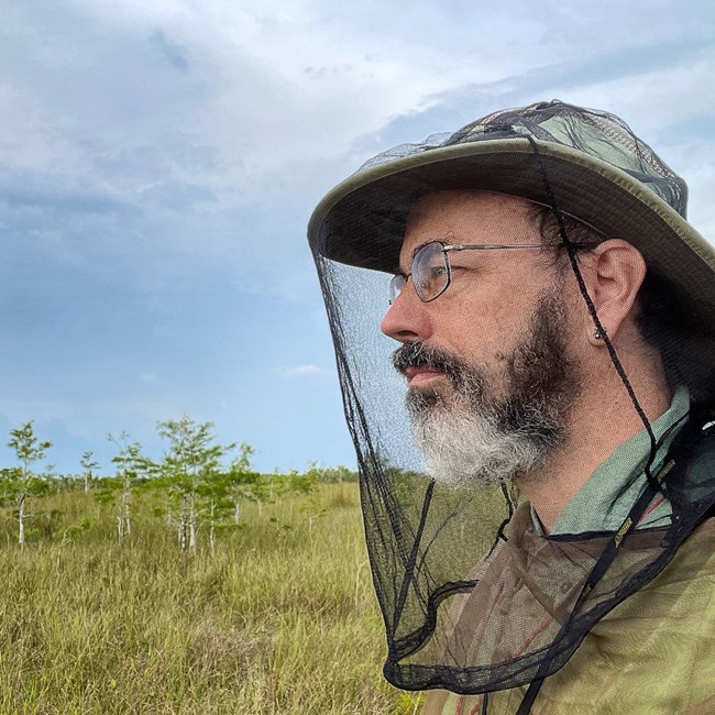 A man wearing a hat with a mosquito net over his face