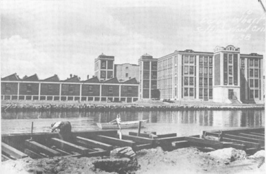 Black and white photo of huge mill complex, with buildings ranging from one to three stories in height.